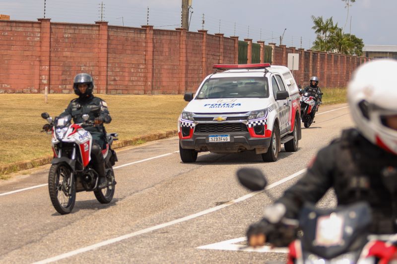Foto de uma viatura da polícia e 3 motos policias em movimento na rua
