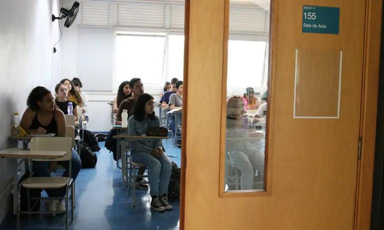 Estudantes sentados em carteiras na sala de aula