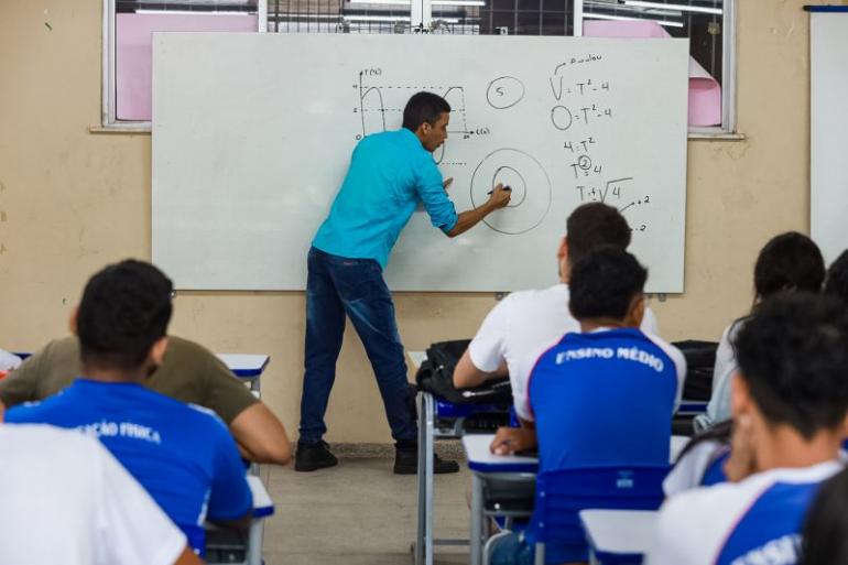 professor escrevendo no quadro e alunos observando 