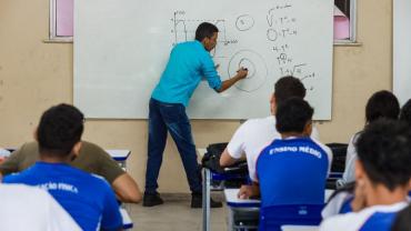 professor escrevendo no quadro e alunos observando 