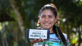 Indígena mostrando o celular com a inscrição "conexão povos da floresta"