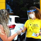 mulher com camisa da camapanha julho amarelo entregando panfleto para outra mulher 